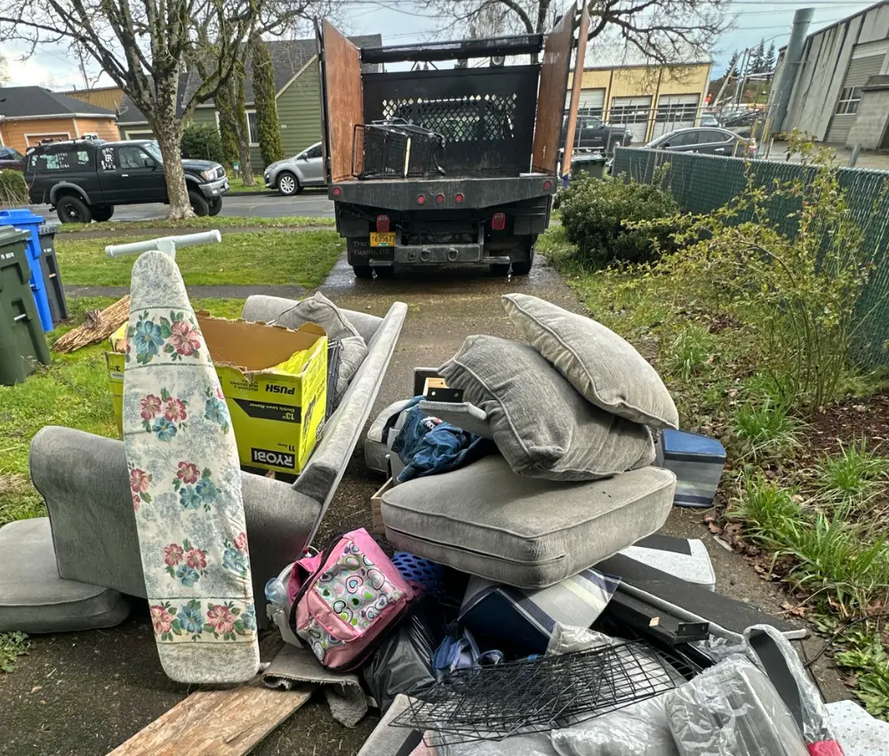 Pile of household debris and furniture in driveway before cleanup